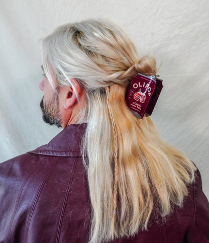 A person shown from the back with long blonde hair clipped to the back with a Olipop Classic Root beer hair claw in their hair