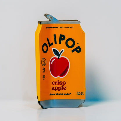 a hair claw designed to look like an Olipop Crisp Apple, featuring a red apple logo and OLIPOP branding, as well as the drink information