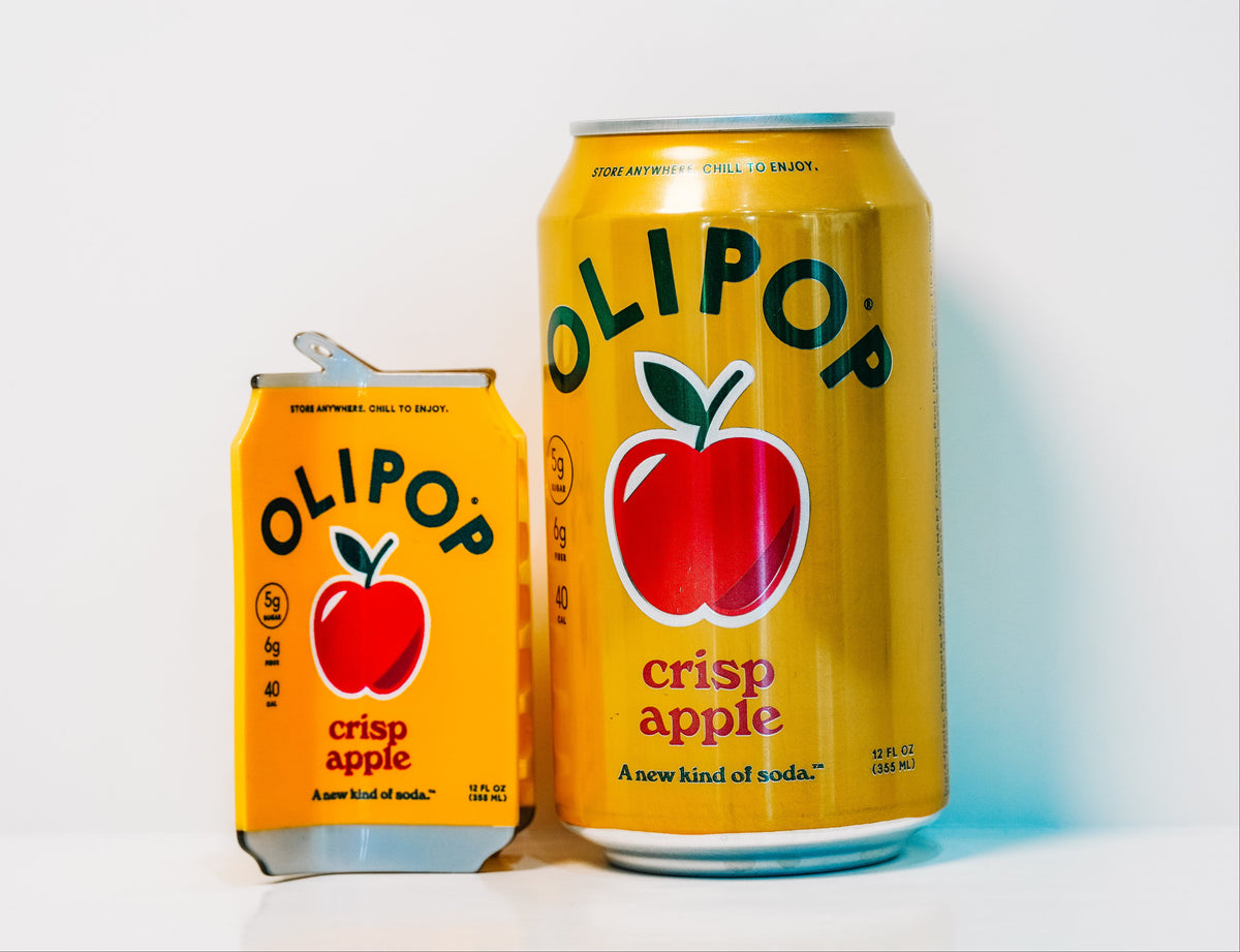 An OLIPOP Crisp Apple Hair Claw sits next to a real can of Crisp Apple olipop