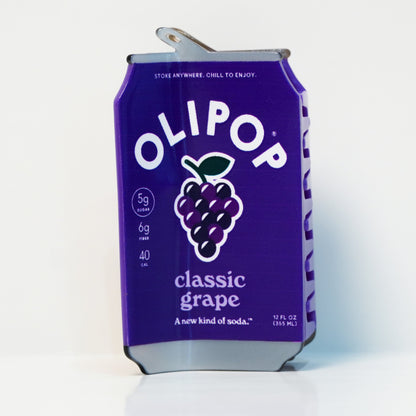 A hair claw designed to look like a can of OliPop Classic Grape soda on a clean white background, featuring the brand name and a purple grape graphic on the front.