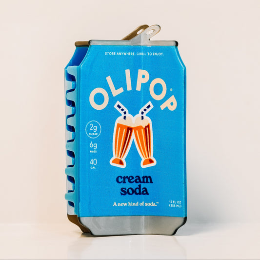 A single Olipop cream soda hair claw. the hair claw is bright blue with white and orange graphics, including the brand name 'OLIPOP' and an illustration of two clinking cream soda glasses.