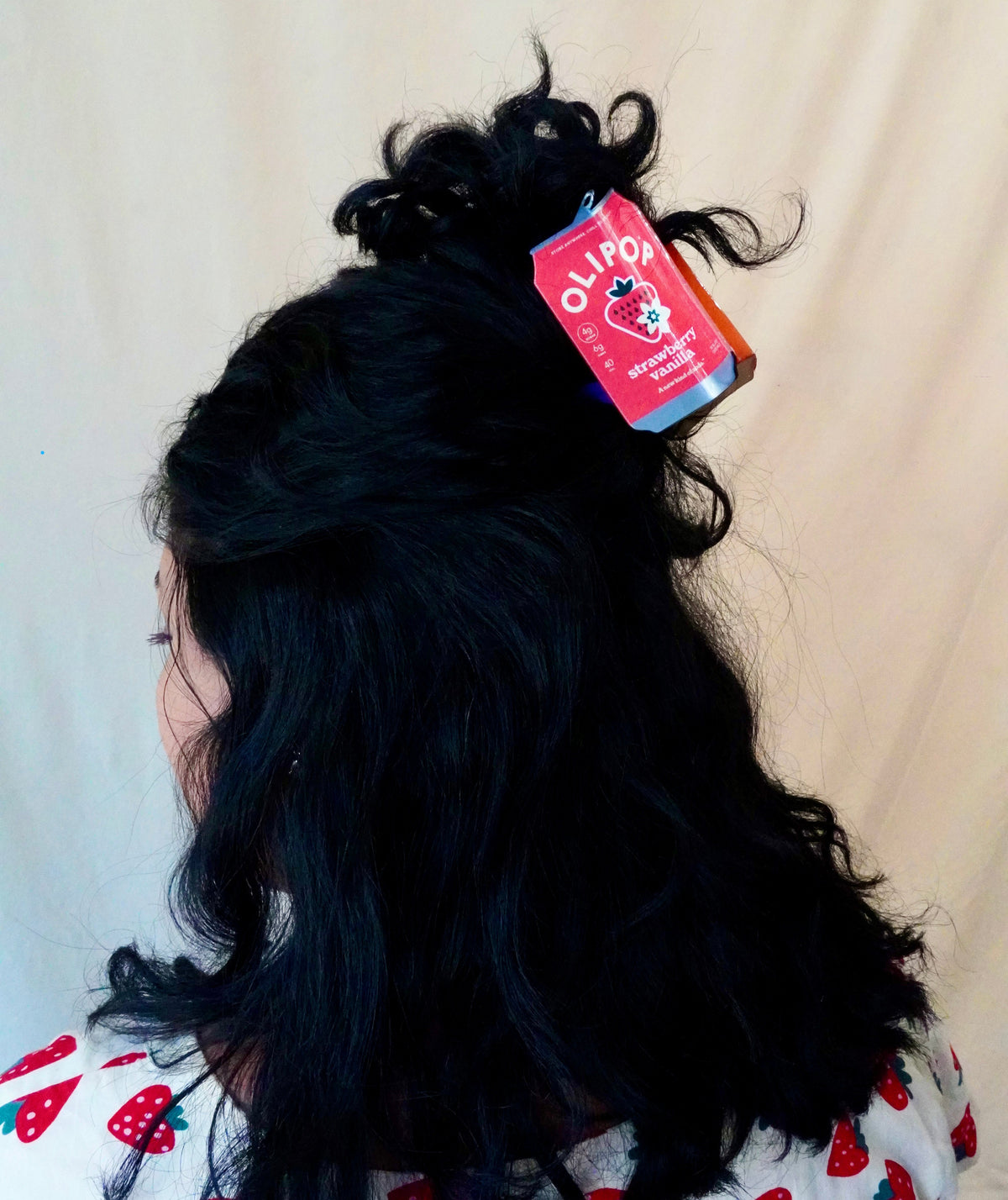 An olipop strawberry vanilla hair claw in dark hair, half up