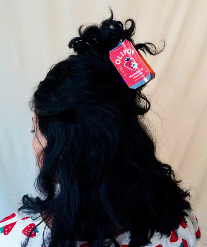 An olipop strawberry vanilla hair claw in dark hair, half up