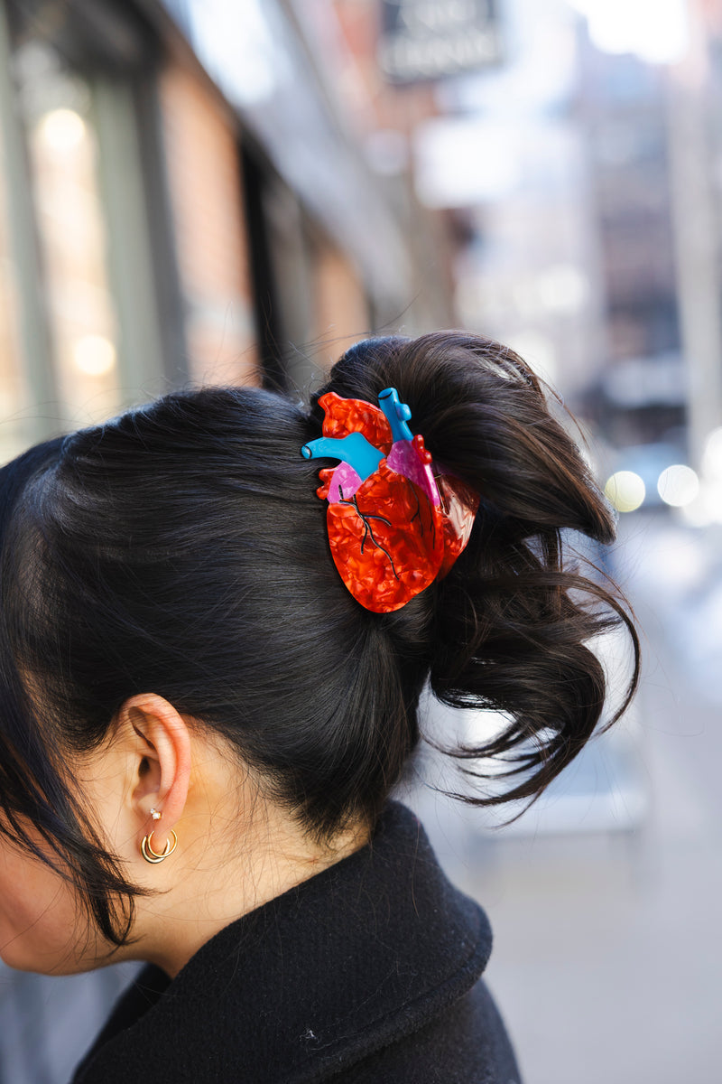 a Person with an anatomical heart hair claw in their hair, blurred background